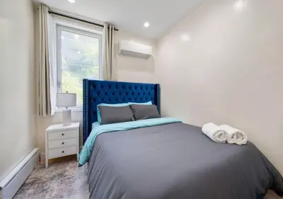 a bedroom with a bed with a blue headboard and a window at Amazing Location Murray Hill 3 Bedroom Apartment ,June to Aug 90 days stay required in New York