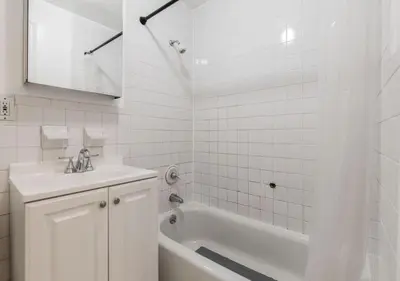 a white bathroom with a tub and a sink at Chelsea 2BR Gem! in New York