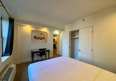 a bedroom with a white bed and a desk at Central Park West Furnished 1 Bedroom Apartment in New York