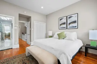 a white bedroom with a large bed and a table at Luxury Townhouse in NYC in New York