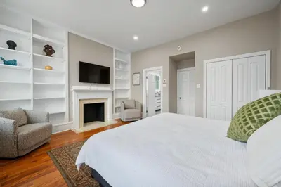 a white bedroom with a bed and a fireplace at Luxury Townhouse in NYC in New York