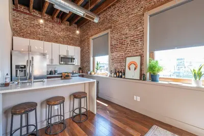 a kitchen with a bar and a brick wall at Stylish SOHO-Inspired Loft, 15 Min to NYC Times Square in Union City