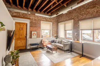 a living room with a brick wall at Stylish SOHO-Inspired Loft, 15 Min to NYC Times Square in Union City