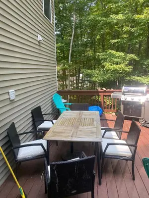 a wooden table and chairs on a deck with a grill at Huge Masthope retreat king sz bed , hot tub , game room in Lackawaxen