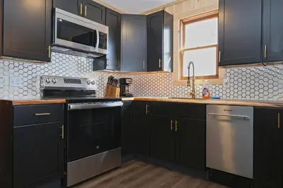 a kitchen with black cabinets and stainless steel appliances at Private Hot tub new 2 Bedroom Home in Catskills in Elka Park