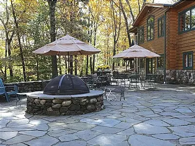 a stone patio with tables and umbrellas in front of a house at Country Getaway Nestled in Enchanting Westchester County near New York City in Bedford