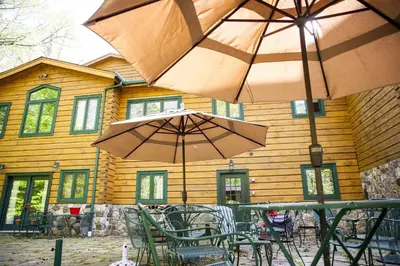 two tables and chairs with umbrellas in front of a building at Lovely Accommodation Surrounded by Stunning Forests in Bedford near New York City in Bedford