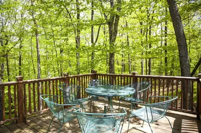 a table and chairs on a deck with trees at Lovely Accommodation Surrounded by Stunning Forests in Bedford near New York City in Bedford
