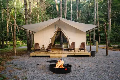 a tent with chairs and a fire in front of it at Large Safari Tent on the Hudson River, Perfect for a Family Glamping Getaway in Corinth