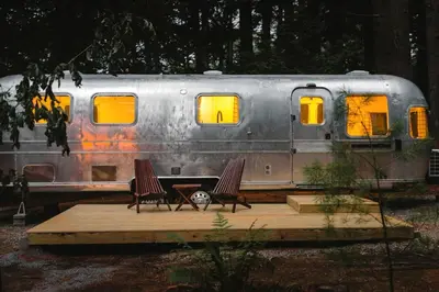 a train car with two chairs in front of it at Waterfront, Pet Friendly Airstream near Lake George in the Adirondack, New York in Corinth