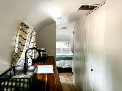 a bathroom with a sink and a bed in a room at Waterfront, Pet Friendly Airstream near Lake George in the Adirondack, New York in Corinth