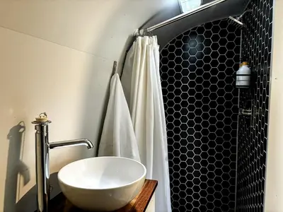 a bathroom with a white sink and a shower at Waterfront, Pet Friendly Airstream near Lake George in the Adirondack, New York in Corinth
