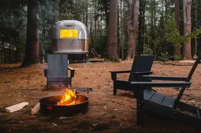 a camp site with a fire and a trailer at Waterfront, Pet Friendly Airstream near Lake George in the Adirondack, New York in Corinth