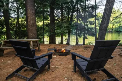 two black chairs and a fire pit in a field at Secluded, Dog Friendly Tiny House on the Hudson River, near Saratoga Springs in Corinth