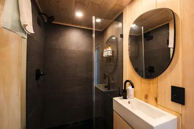 a bathroom with a shower and a sink and a mirror at Secluded, Dog Friendly Tiny House on the Hudson River, near Saratoga Springs in Corinth