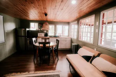 a kitchen and dining room with a table and a couch at Rustic, Pet Friendly Cabin on the Hudson River, Perfect for a Glamping Weekend in the Adirondacks in Corinth