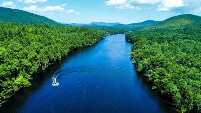 an aerial view of a river with a boat in the middle at Rustic, Pet Friendly Cabin on the Hudson River, Perfect for a Glamping Weekend in the Adirondacks in Corinth