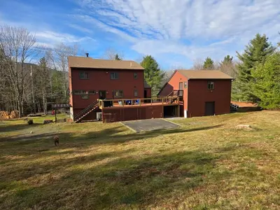 a house on a hill with a dog in front of it at Wilderness Getaway in East Jewett