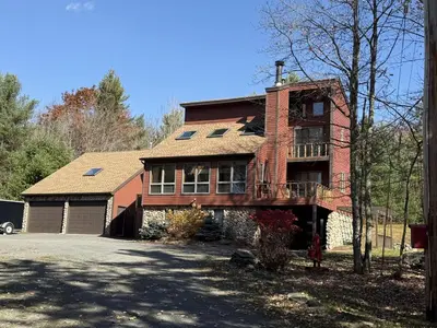 a large brick house with a balcony on a driveway at Wilderness Getaway in East Jewett