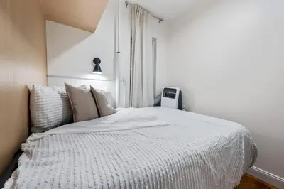 a white bed in a room with a window at 2BR Upper East Side near Central Park in New York