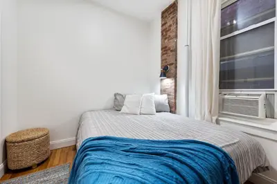 a bedroom with a bed with a blue blanket and a window at 2BR Upper East Side near Central Park in New York