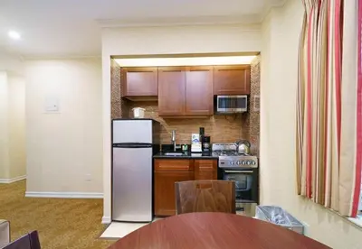 a kitchen with a stainless steel refrigerator and a table at 3BR Apartment in Big Apple in New York