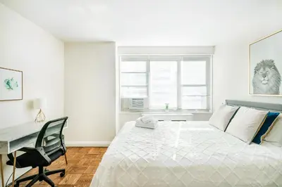 a white bedroom with a bed and a desk at Lovely and Comfy Studio in NYC in New York