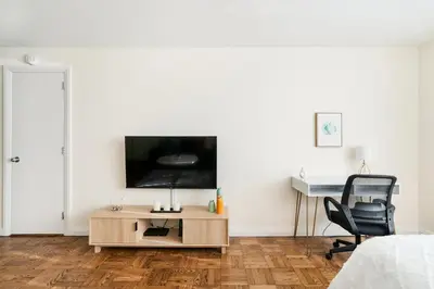 a bedroom with a tv and a desk and a chair at Lovely and Comfy Studio in NYC in New York