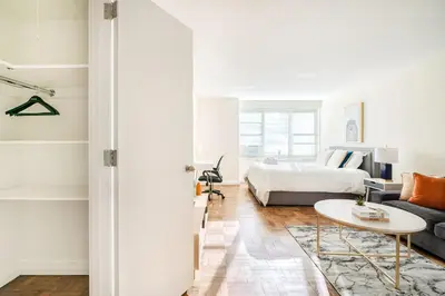 a white bedroom with a bed and a table at Lovely and Comfy Studio in NYC in New York