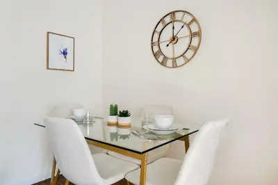 a dining room table with white chairs and a clock at Lovely and Comfy Studio in NYC in New York
