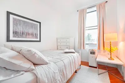 a white bedroom with a bed and a window at Prime Location Upper Manhattan Furnished Apartment in New York