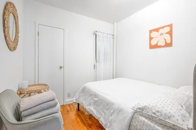 a white bedroom with a bed and a chair at Lovely Apt Near Central Park in New York