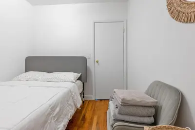 a white bedroom with a bed and a chair at Lovely Apt Near Central Park in New York