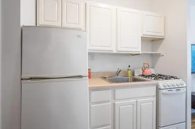 a kitchen with white cabinets and a white refrigerator at Lovely Apt Near Central Park in New York
