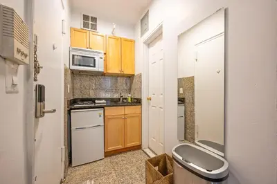 a small kitchen with wooden cabinets and white appliances at Amazing Studio in Kips Bay in New York