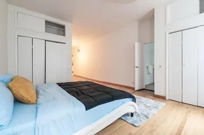 a bedroom with a bed with a blue comforter at XL Prime Tribeca Furnished Loft in New York