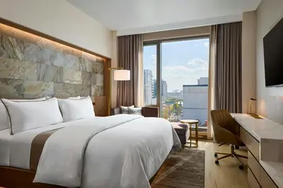 a hotel room with a bed and a desk and a window at The Westin Flushing LaGuardia Airport in Flushing