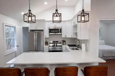 a kitchen with white cabinets and a kitchen island with chairs at Modern Retreat Poconos 3BR Fire Pit Skiing in East Stroudsburg