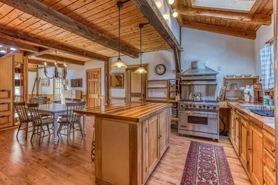 a large kitchen with wooden cabinets and a table at Light-filled Carpenter's Cottage in Stockbridge in Stockbridge