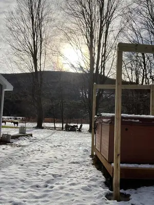 a snow covered yard with a wooden gate and trees at The Cabins at Walnut Grove-minutes from Hunter and Windham in Ashland