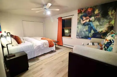 a bedroom with a bed and a couch and a painting at Villa MiaNova A Modern Hideout in the Woods in Lake Ariel