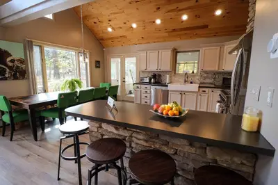 a kitchen with a stone counter and a table with a bowl of fruit at Villa MiaNova A Modern Hideout in the Woods in Lake Ariel
