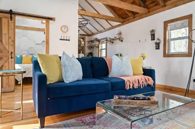 a blue couch in a living room with a glass table at Perfect Couples Cabin Fireplace Firepit & Wine Nearby in Hawley