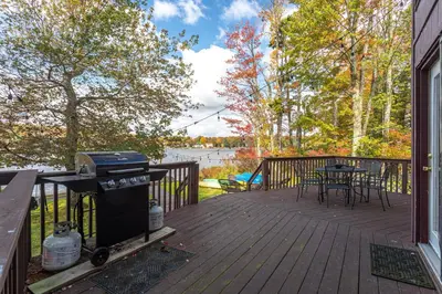 a grill on a deck with a table and chairs at Water Front Dream Hot Tub Fire Pit King Bed in Tobyhanna