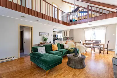 a living room with a green couch and a dining room at Game Room Fire Pit Dog Friendly in Tobyhanna
