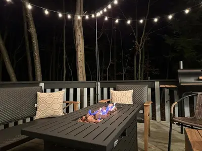 a wooden table with a fire pit on a deck with lights at Game Room Fire Pit Dog Friendly in Tobyhanna