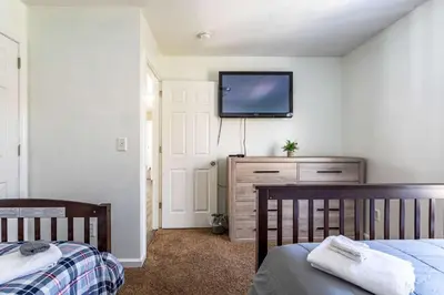 a bedroom with two beds and a tv on the wall at Lakeside Haven 5 BDR Fire Pit Pet Friendly in Tobyhanna