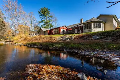 a house on a hill next to a river at Heated Indoor Private Pool Stream Front Game Room in Cresco