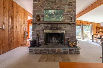 a living room with a stone fireplace in a house at Whispering Pines Chalet Game Room Fire Pit in Pocono Pines