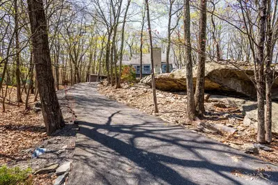 a path in the woods with a house in the background at Cozy 3BD 2Minutes from Beach in East Stroudsburg